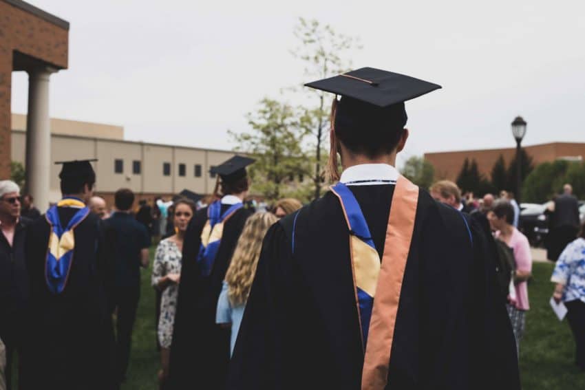 Marketing degree graduate in cap and gown outside