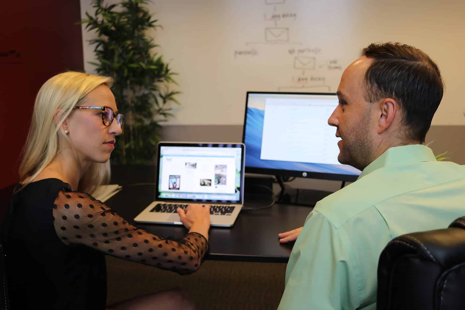 Female and male colleagues at a desk with laptops