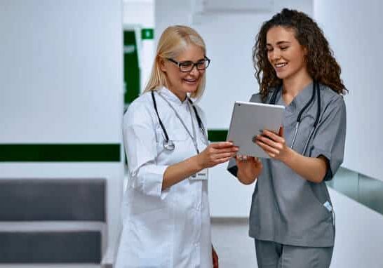 Doctors laugh and talk in the hallway. Older woman and young female doctors.