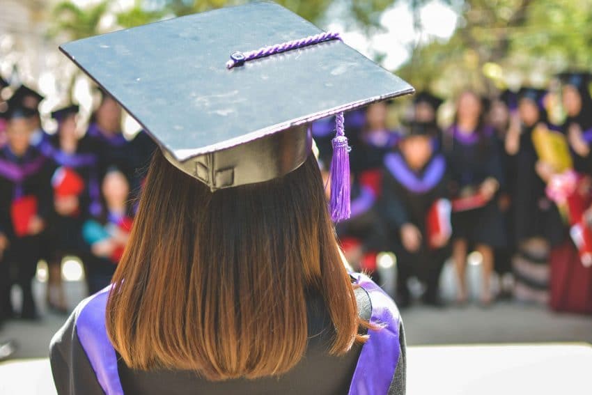 female graduate facing classmates