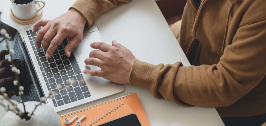 UoPeople student on laptop with notebooks attending online college