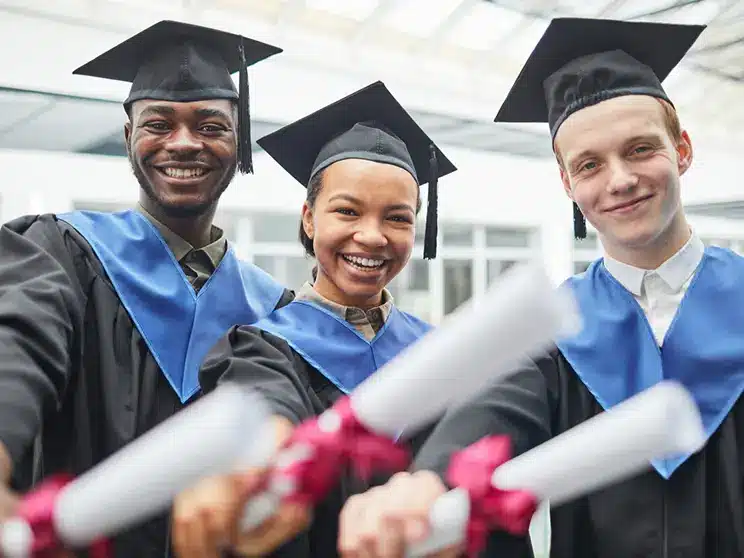 male computer science graduates holding degrees and wearing graduation caps