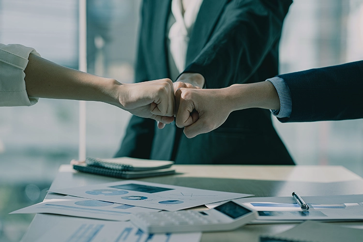 three emotionally intelligent corporate leaders joining hands together over an office desk